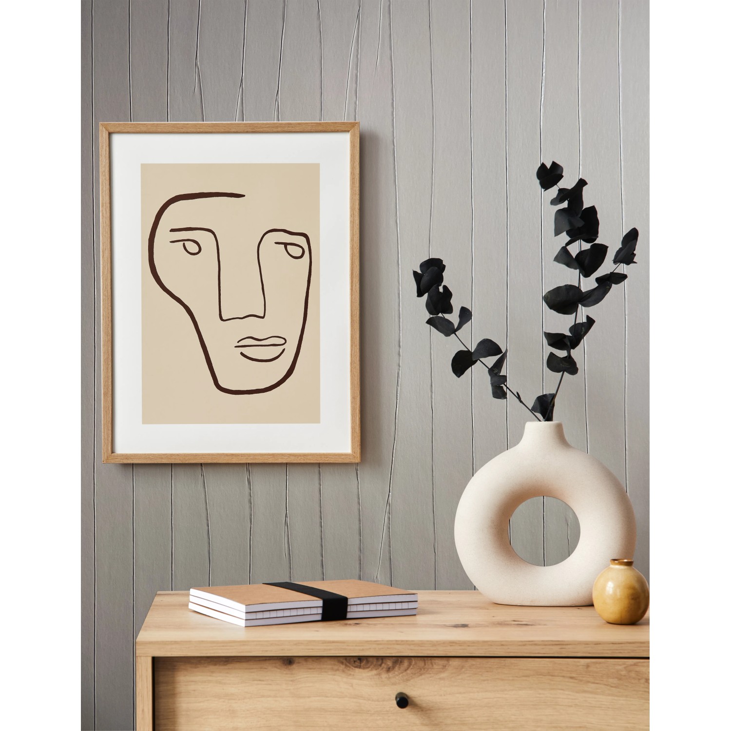 Moderne Vliestapete in Creme mit abstraktem Gesicht-Motiv im Bilderrahmen an der Wand.
