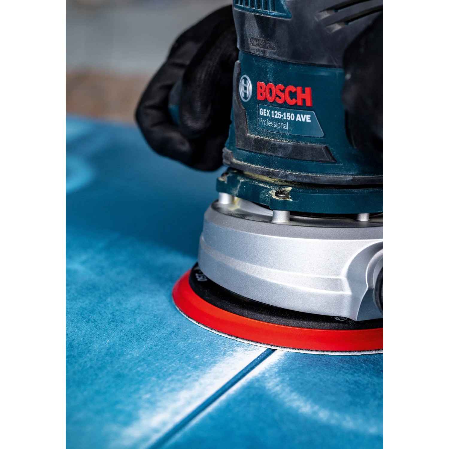Bosch Exzenterschleifer mit Schleifblatt C470 K60 beim Schleifen einer blauen Oberfläche.