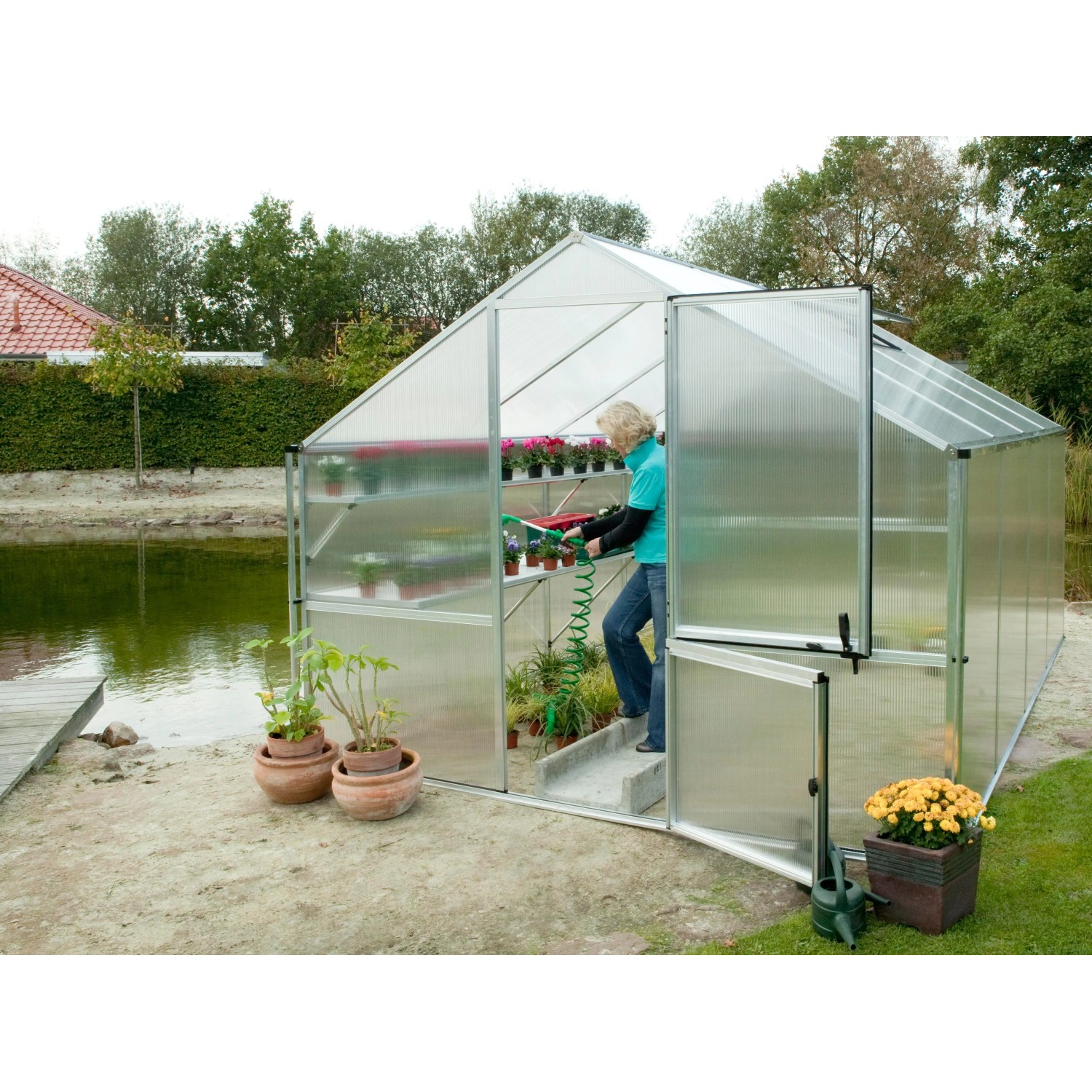KGT Gewächshaus Orchidee Alu blank, 12,74 m², mit offener Tür und Person beim Gießen von Pflanzen.