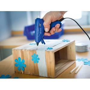 LUX Heißklebepistole im Einsatz beim Basteln mit Holz und blauen Deko-Blumen.