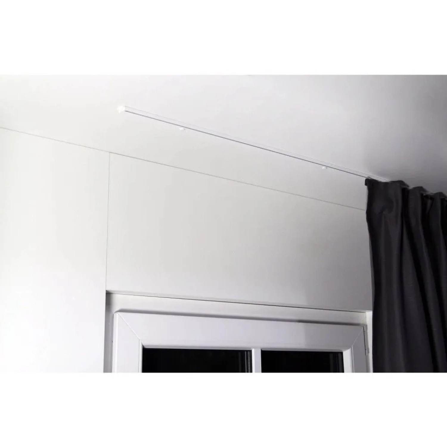Weiße, minimalistische 1-Lauf Gardinenschiene zur Deckenmontage über einem Fenster mit dunklem Vorhang. Dekoartikel.