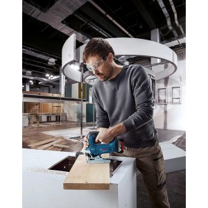 Mann sägt Holz mit Bosch Professional Akku-Stichsäge GST 18 V-125 B.