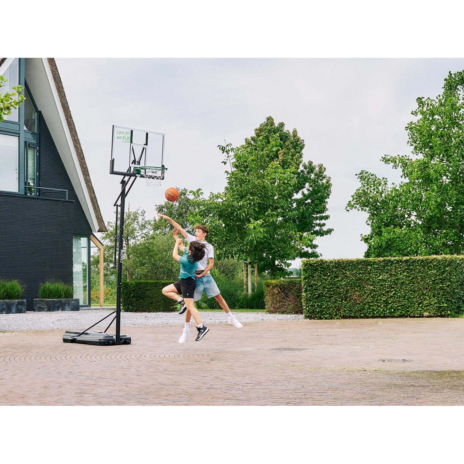 Salta Basketballständer Center mit zwei spielenden Jugendlichen im Garten.