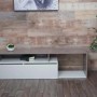 Modernes TV-Rack in Beton-Optik und Weiß mit Staufach und offenen Ablagen.