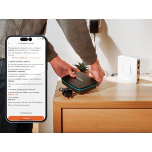 Gardena Smart Gateway Verbindungsgerät in Nutzung, mit Smartphone und Zubehör auf Tisch.