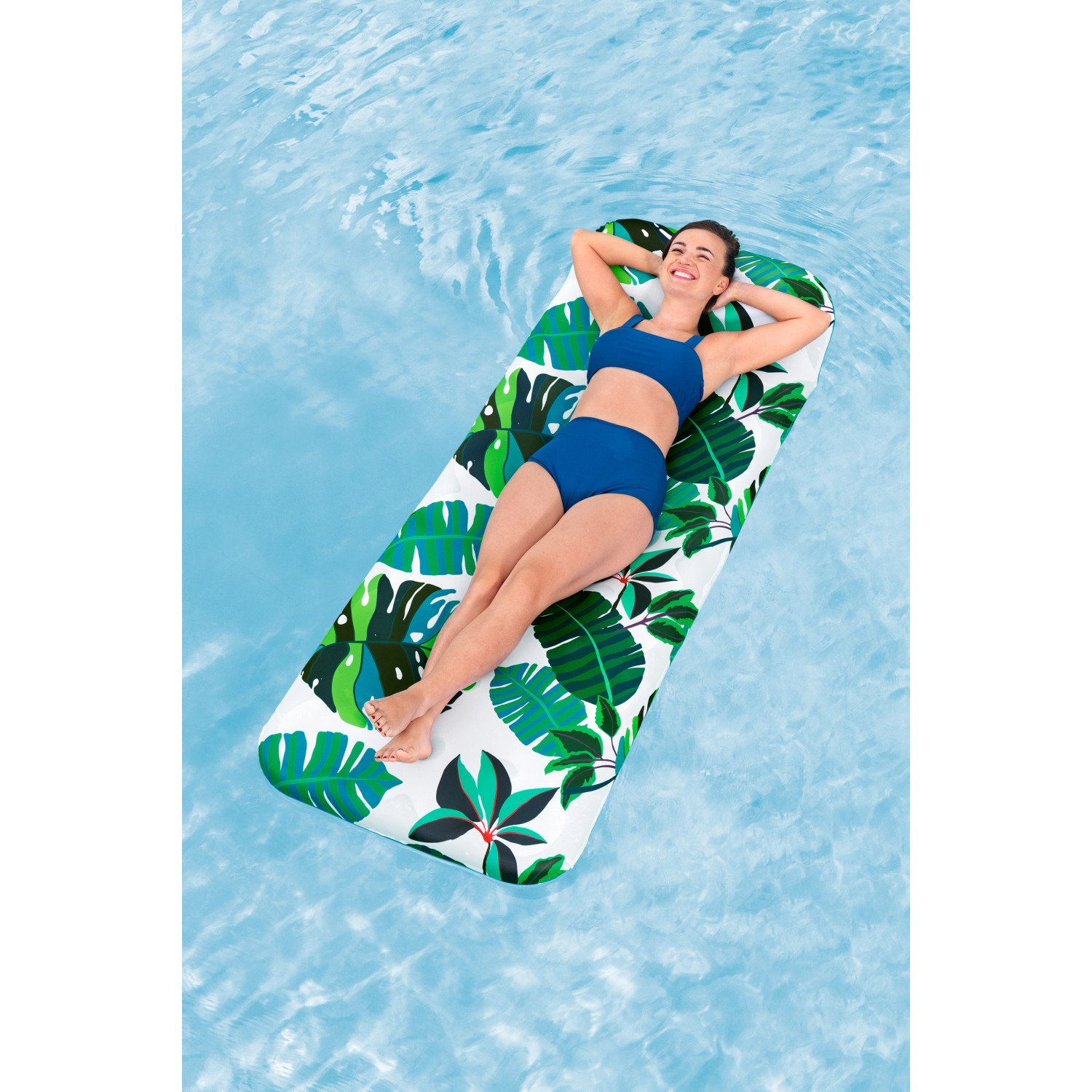 Frau entspannt auf Bestway Luftmatratze Blissfull Drifter mit tropischem Muster im Pool.
