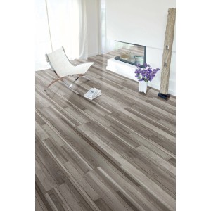 Verlegtes Kaindl Comfort Laminat 7mm Driftwood Oak Grau im Raum mit Stuhl und Deko.