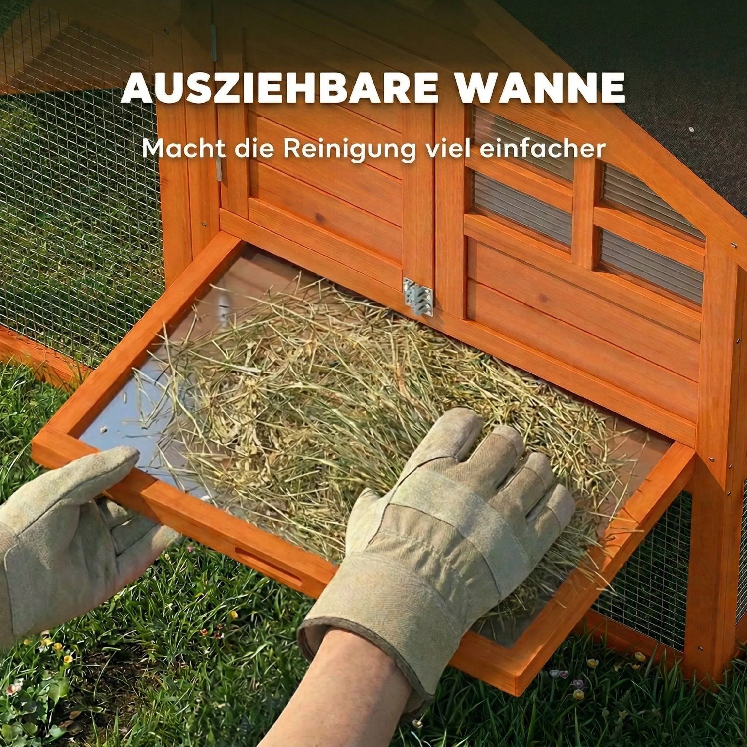 Hand zieht ausziehbare Wanne mit Heu aus orangefarbenem PawHut Kaninchenstall aus Tannenholz zur einfachen Reinigung.
