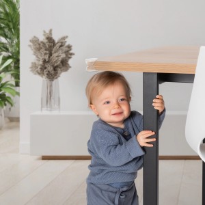 Kleinkind steht an Tisch mit transparenten Reer Eckenschutz. Vorteilspack mit 12 Stück.