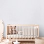 Kinderzimmer mit weißer Uni Vliestapete von A.S. Creation hinter einem Babybett.
