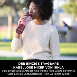 Frau trinkt aus Cranberry-farbenem Ninja Mixer Blast. Kabelloser, tragbarer Mixer für Smoothies.