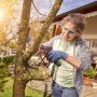 Frau sägt Ast mit Bosch Akku-Säge EasyCut 12 mit NanoBlade-Technologie im Garten.