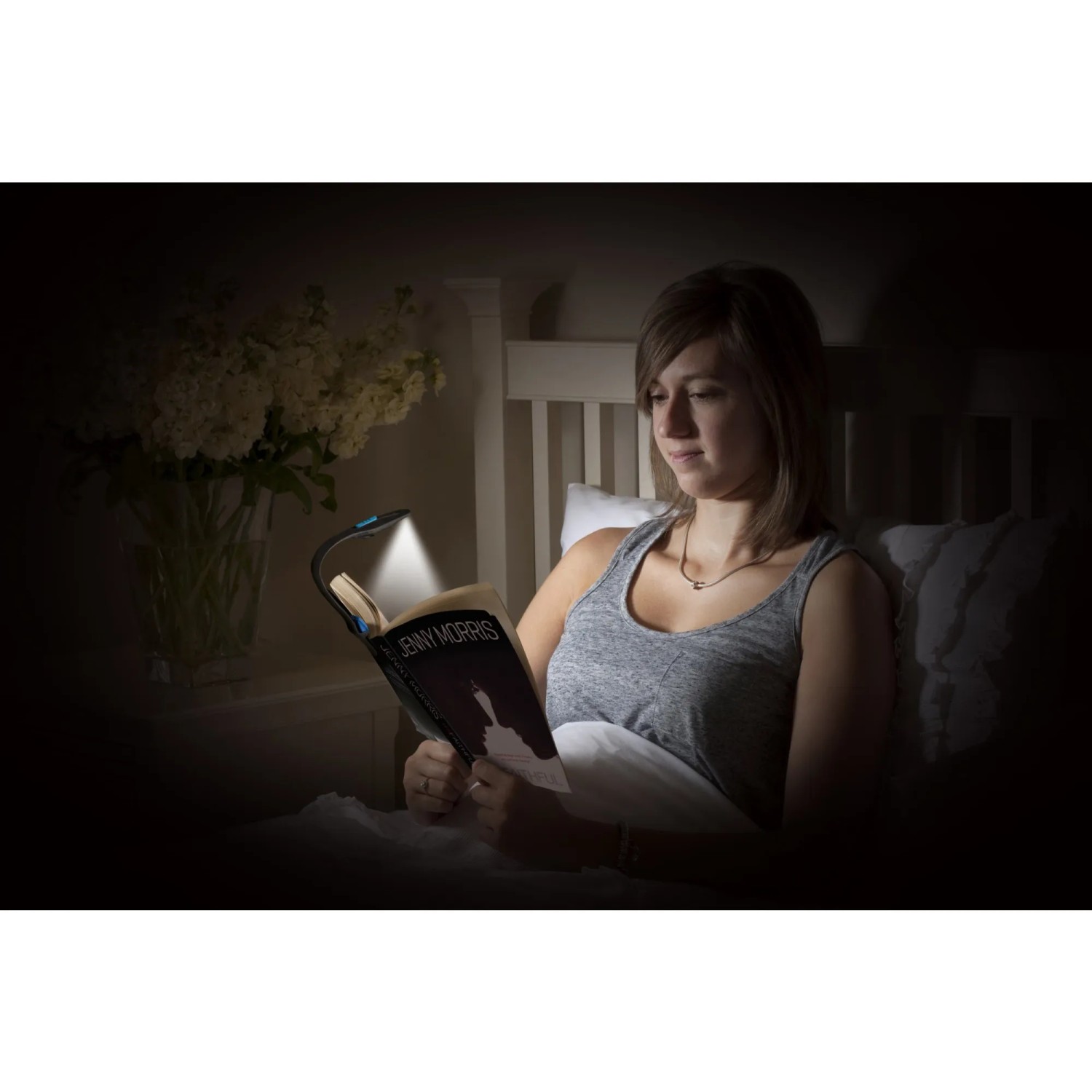 Frau liest mit Energizer Booklight LED-Taschenlampe im Bett. Leselampe mit flexiblem Hals.