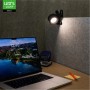 Schwarze LED Akku Tischlampe mit Clip an einer Wand über einem Schreibtisch mit Laptop.