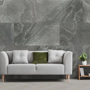 Graues Echtstein-Paneel Real Stone Schiefer an einer Wand hinter einem Sofa. Strukturierte Oberfläche, Natursteinoptik, Verblender.