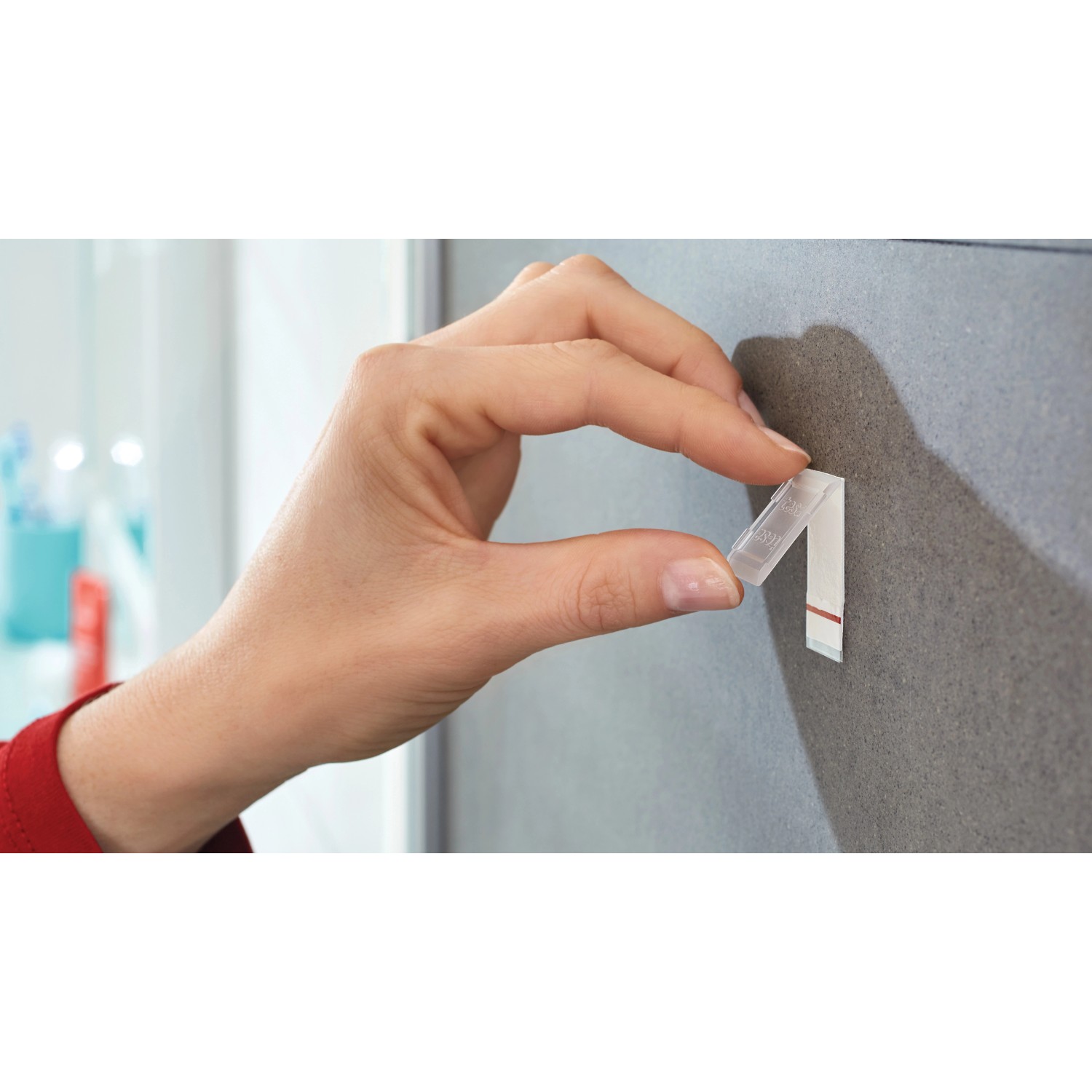 Hand befestigt Tesa Powerstrips Haken Waterproof an Fliese. Klebehaken aus Edelstahl, wasserfest.