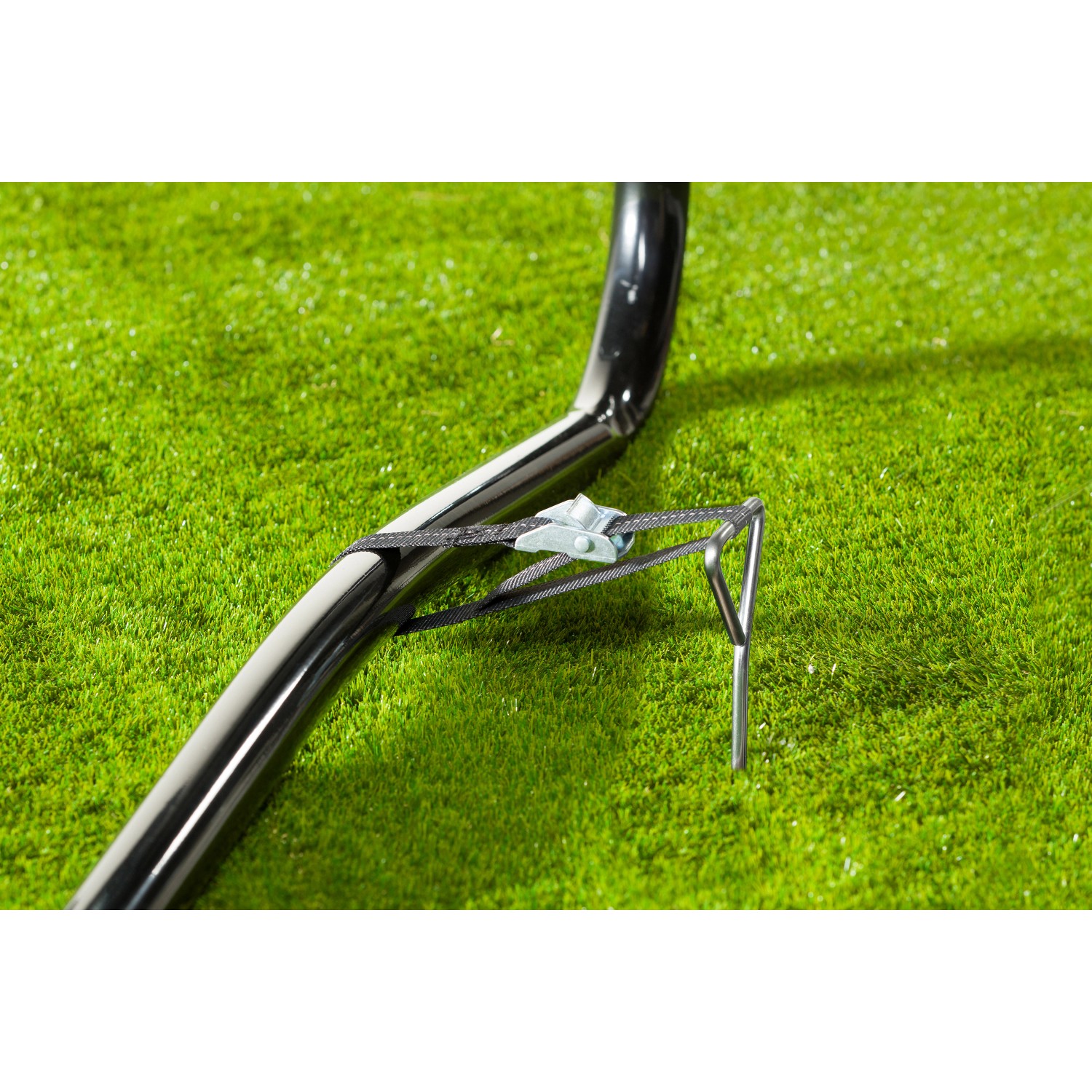 Detailaufnahme: Trampolin-Befestigungsset mit Erdanker und Spanngurt zur sicheren Fixierung.