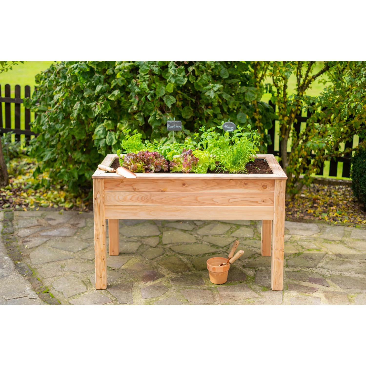 Westmann Hochbeet aus Lärchenholz, 120x65x75 cm, bepflanzt mit Salat und Kräutern im Garten.