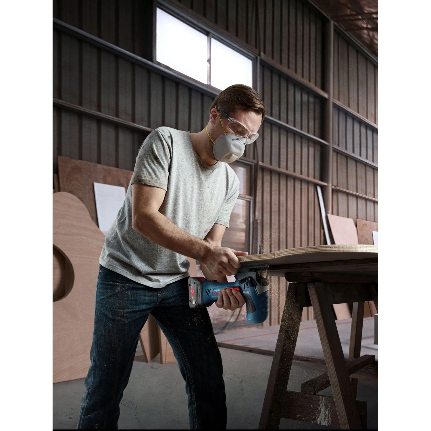 Mann mit Schutzbrille sägt Holz mit Bosch Professional Akku-Stichsäge GST 18 V-125 S.