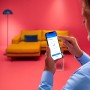Mann steuert WiZ LED-Deckenleuchte Adria per Smartphone App.