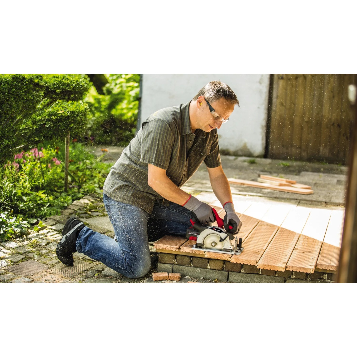 Mann sägt Holz mit der Einhell Akku-Handkreissäge TE-CS 18/150 Li Solo im Garten.
