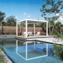 Weißer Weide Deluxe Plus Aluminium Pavillon mit elektrischem Lamellendach am Pool auf Holzterrasse.