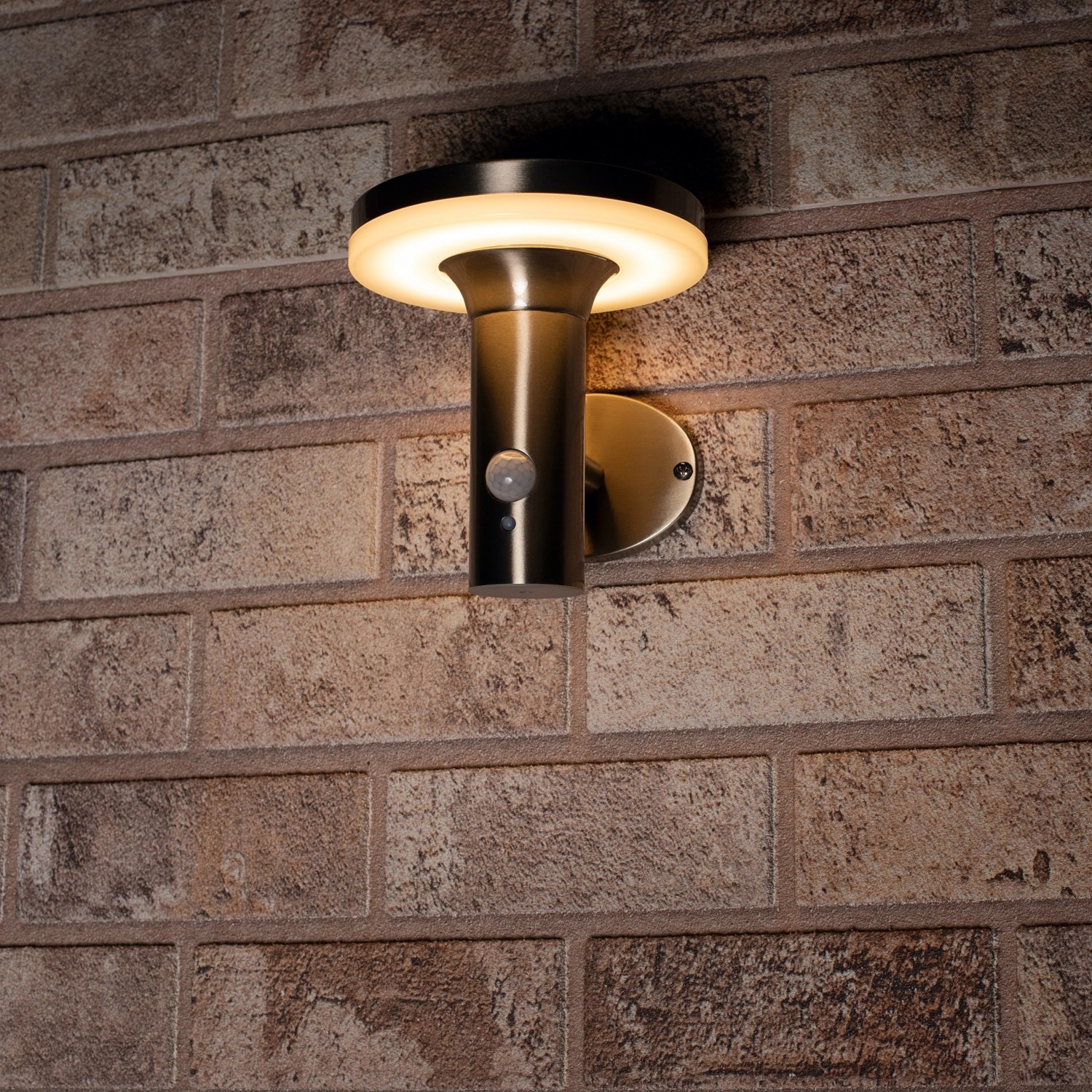 Solar-Wandleuchte Sevilla aus rostfreiem Stahl mit Sensor an einer Backsteinwand.