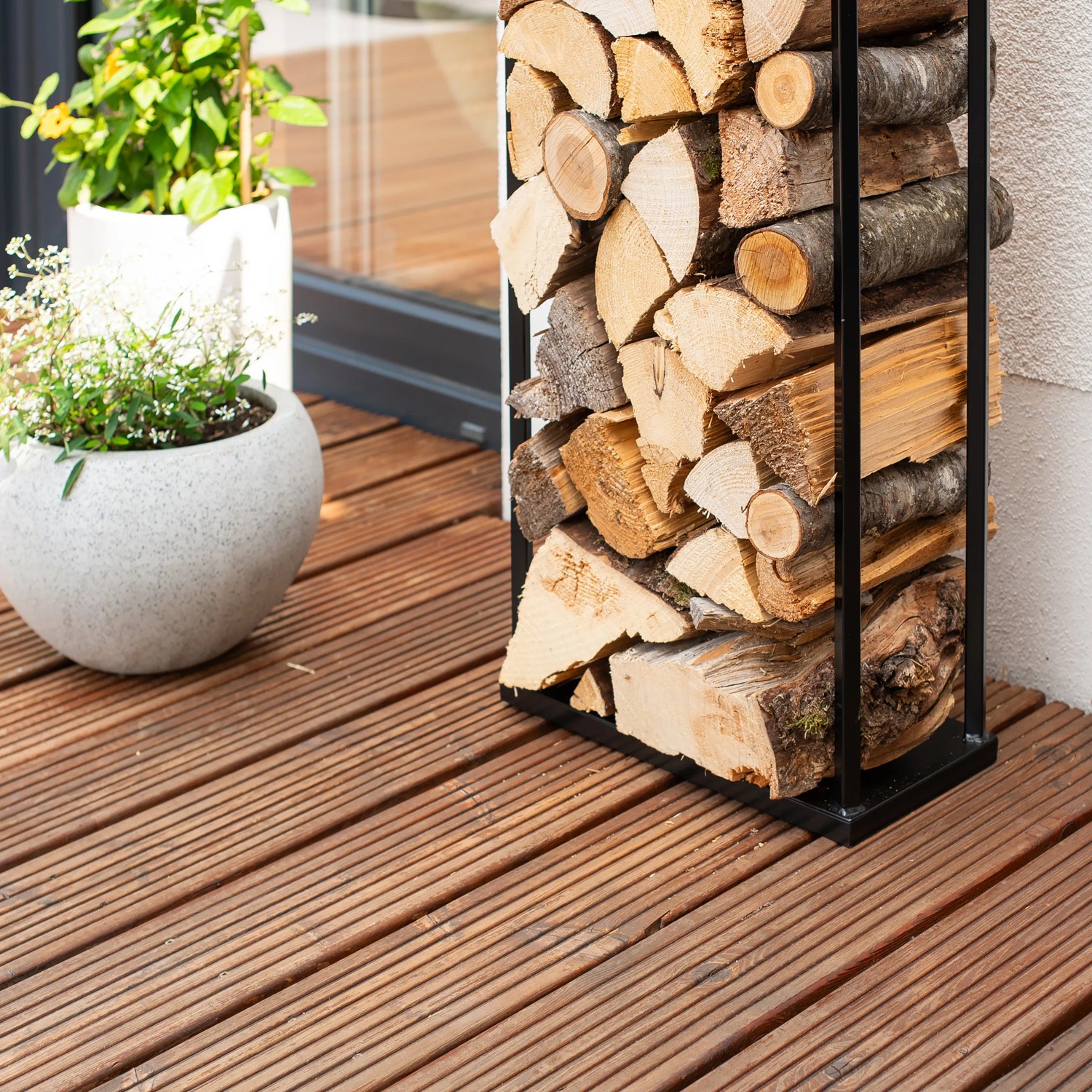 Schwarzes Westmann Kaminholzregal Xavier aus Stahl, gefüllt mit Holzscheiten. Schlankes Design für drinnen und draußen.