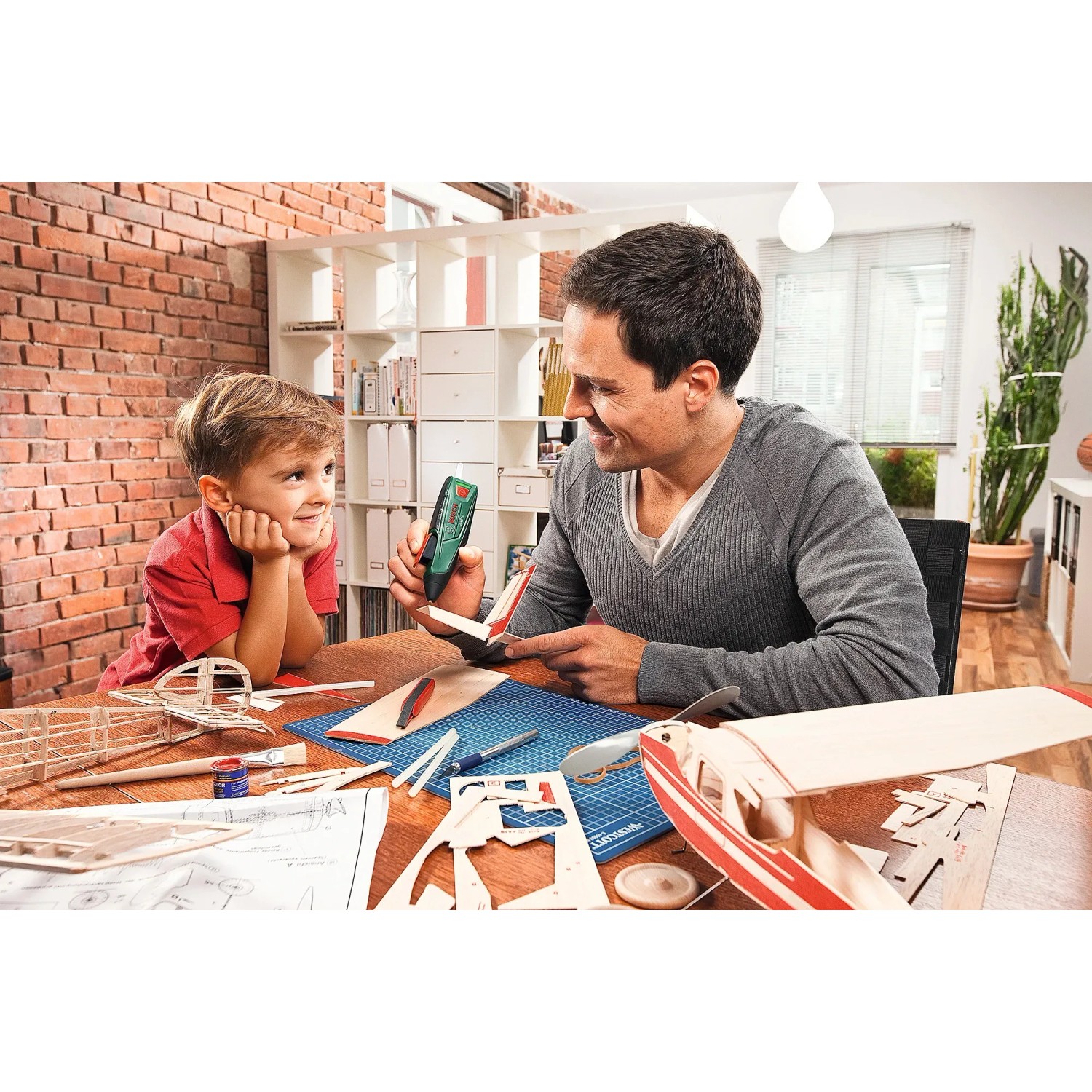 Bosch Akku-Heißklebepistole GluePen beim Basteln mit Kind. Kabelloser Heißklebestift für Modellbau.