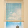 Naturfarbenes OBI Bambus-Raffrollo (80x160cm) am Fenster mit blauem Himmel im Hintergrund.