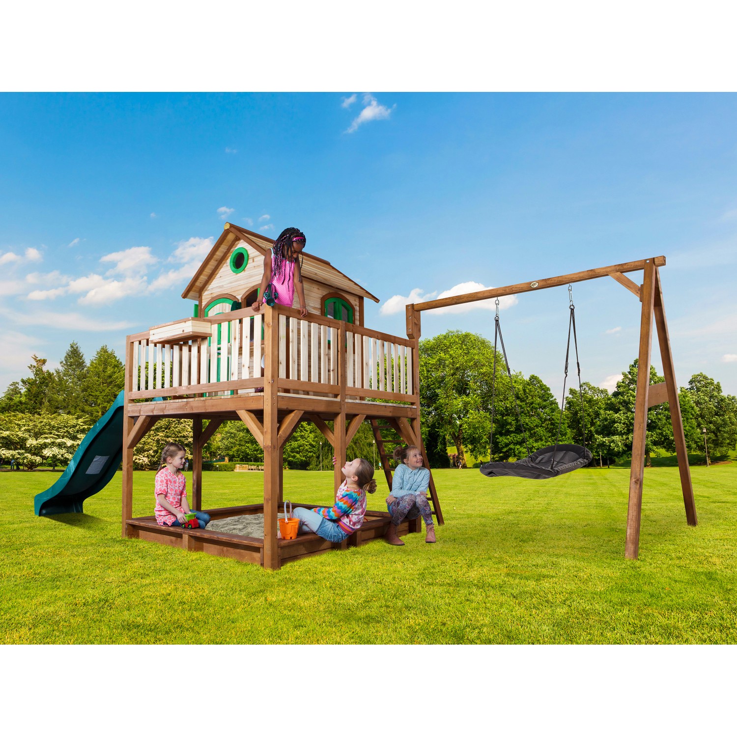 Axi Liam Spielhaus mit Nestschaukel und Rutsche im Garten mit spielenden Kindern.