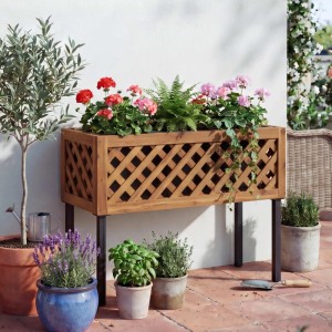 Braunes Akazienholz Hochbeet mit Rankgitter-Design und schwarzen Metallfüßen, bepflanzt mit Blumen auf Terrasse.