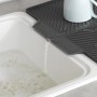 Graue Wenko Abtropfmatte Nelia Maxi aus Kunststoff mit Tasse auf einer Spüle, Wasser läuft ab.