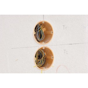 Zwei Hohlwanddosen-Löcher mit Kabeln in einer Wand, vorbereitet mit der wolfcraft Schablone.