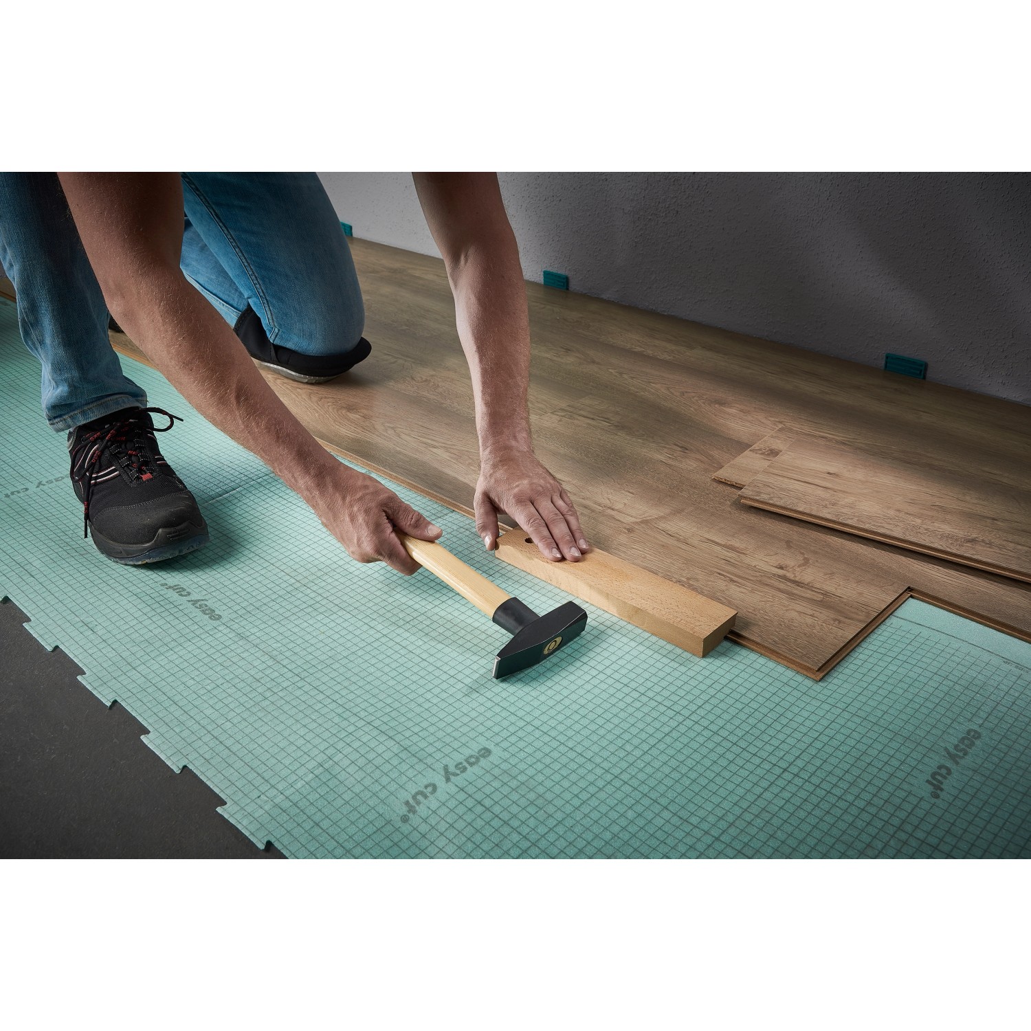 Verlegen von Laminat mit dem wolfcraft Verlege-Set: Zugeisen, Schlagholz und Keile im Einsatz.