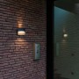 Anthrazitfarbene Lutec LED-Außenwandleuchte Lotus mit Up & Down Lichteffekt an einer Backsteinwand.