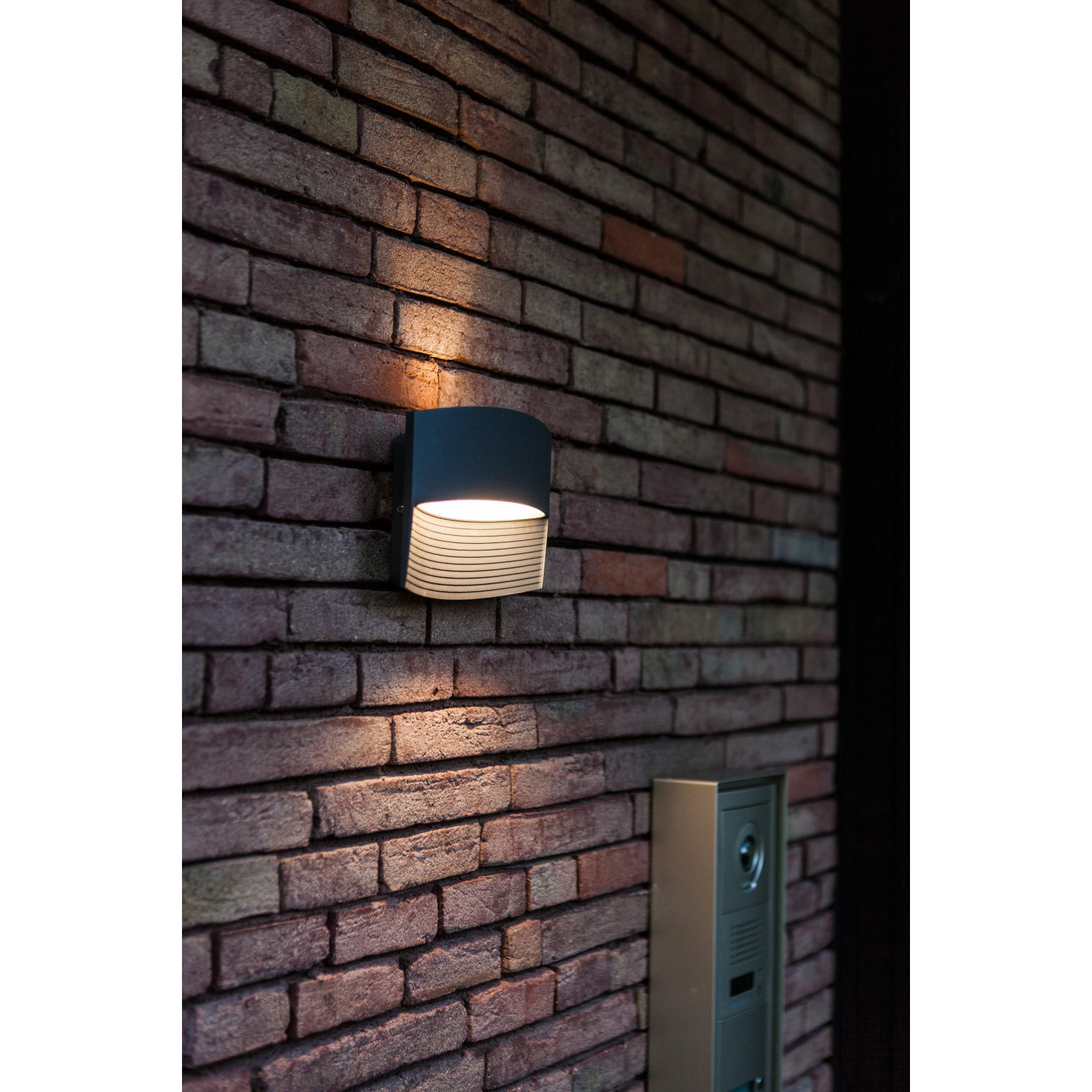 Moderne Lutec LED-Außenwandleuchte Lotus in Anthrazit mit Up & Down Lichteffekt an einer Backsteinwand.