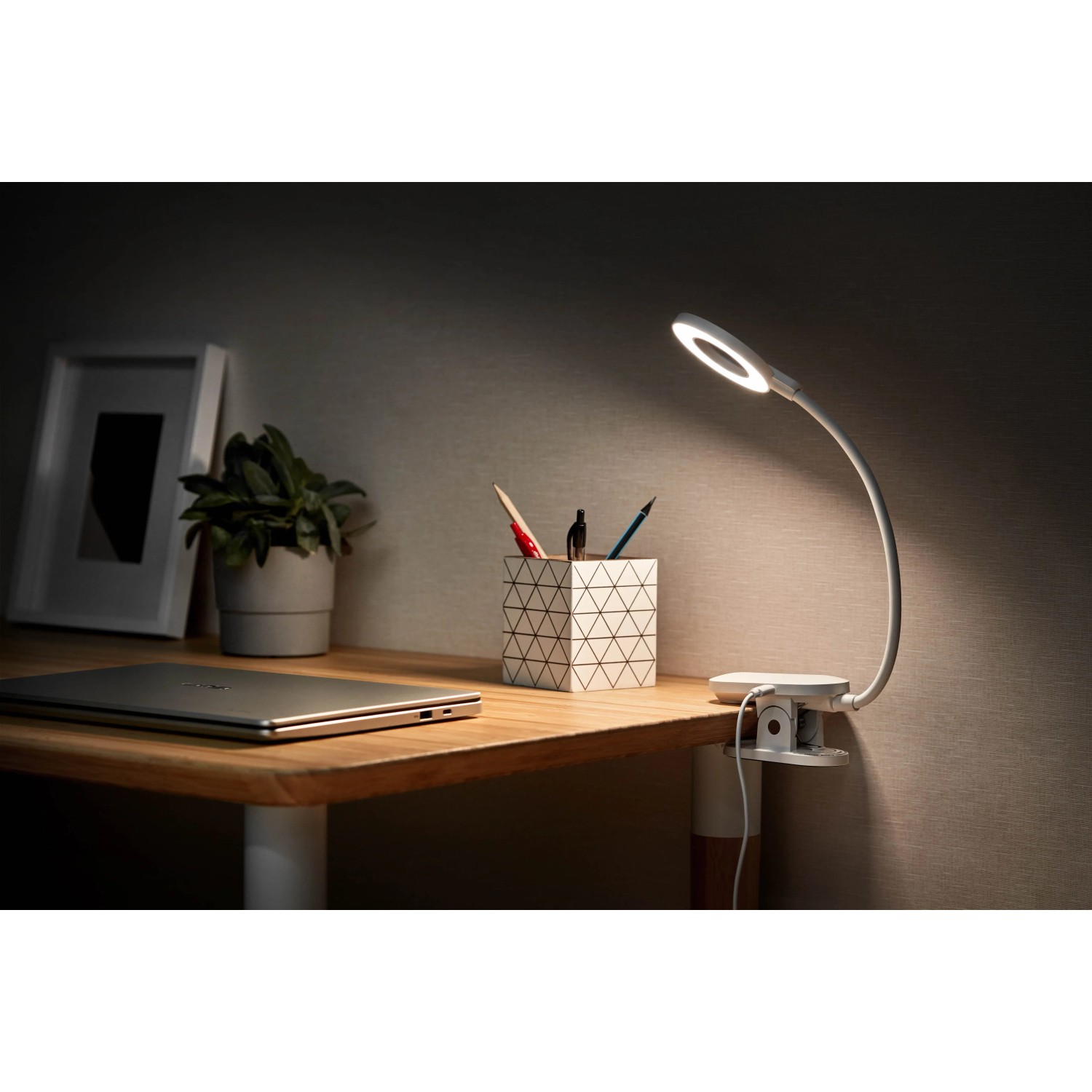 Philips Forys LED-Tischleuchte mit Clip und Akku auf Schreibtisch, Licht an.