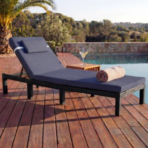 Anthrazitfarbene Poly-Rattan Sonnenliege mit grauen Kissen am Pool.