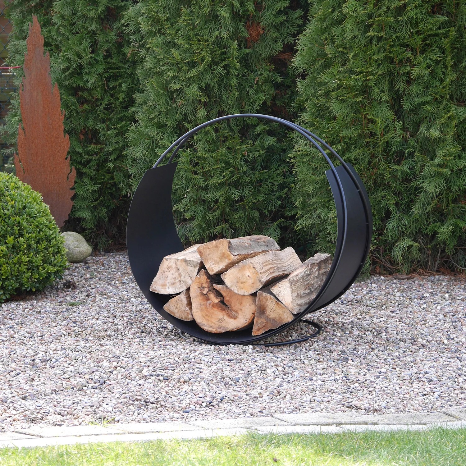 Schwarzer Vasner Kaminholzkorb Situro S1 mit Holzscheiten im Garten.