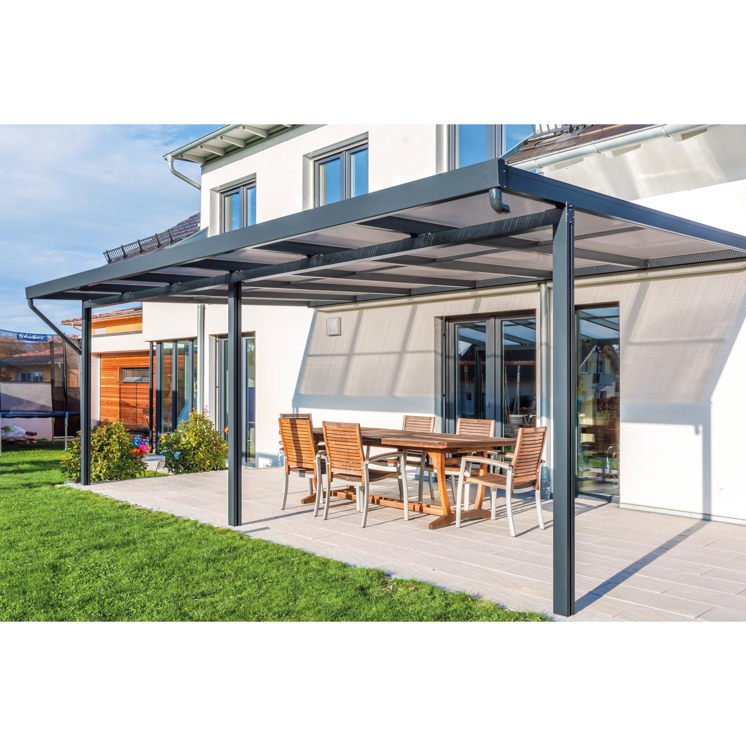 Anthrazitfarbenes Gutta Terrassendach Premium mit Stegplatten aus Polycarbonat und Esstischgruppe.