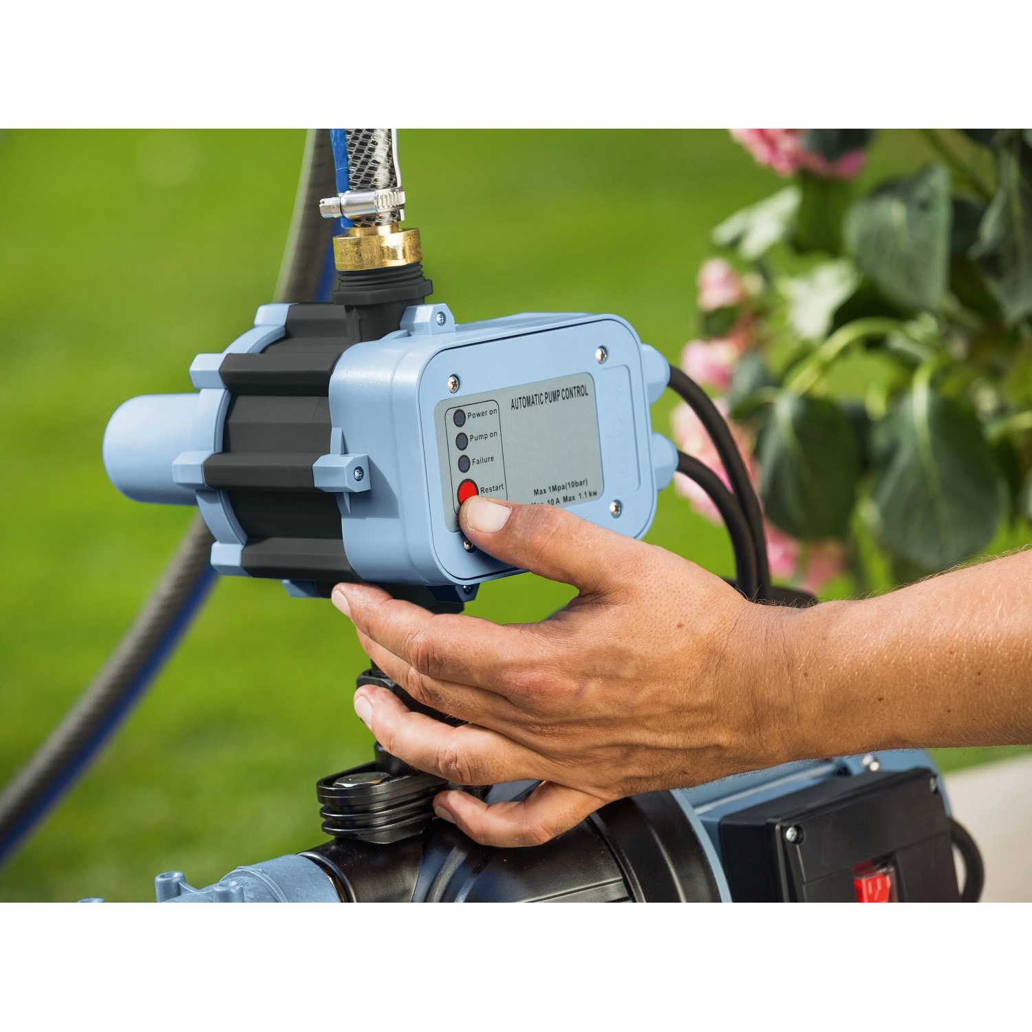 Elektronischer Druckschalter EDS 8 für Gartenpumpen, bedient von einer Hand.