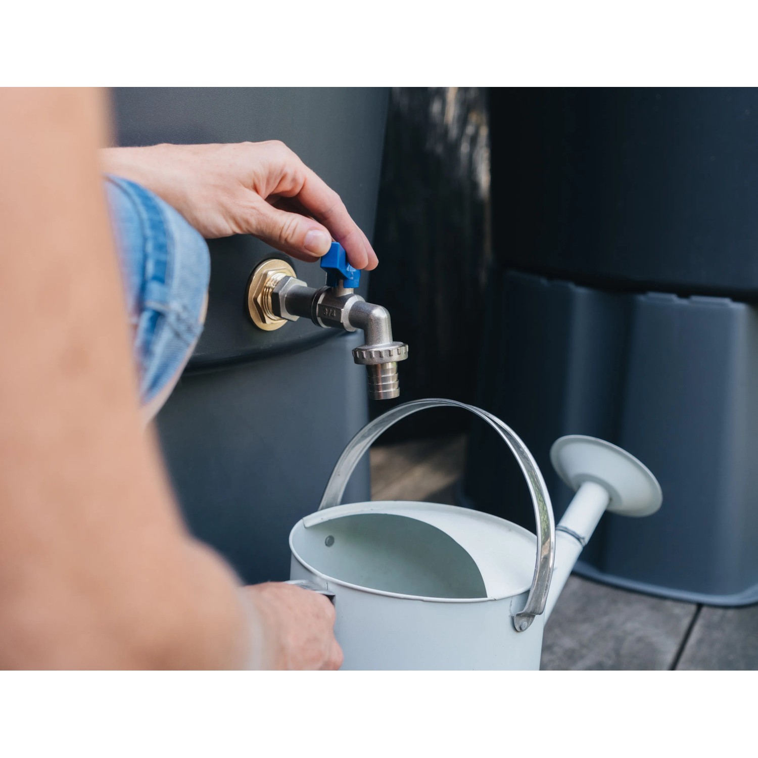 Regentonnenanschluss aus Messing (3/4 Zoll) mit Wasserhahn und Gießkanne in Nutzung.