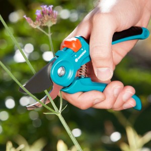 Hand schneidet Pflanze mit Gardena Gartenschere B/S. Bypass-Schere mit Antihaftbeschichtung.