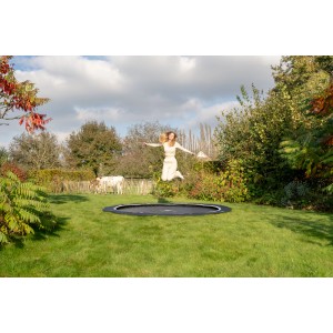 Schwarzes Exit InTerra Bodentrampolin Ø 244 cm mit springender Person im Garten.