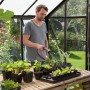 Mann bewässert Pflanzen mit Gardena Comfort Gartenbrause im Gewächshaus.