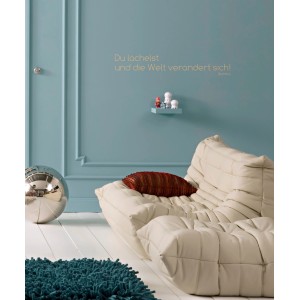 Wandtattoo Komar Deko-Sticker Du Lächelst, 14x70 cm, an blauer Wand über Sofa.