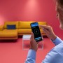 Mann steuert WiZ LED Stehleuchte per App. Smarte Lampe mit Farbwechsel für Wohnraum.