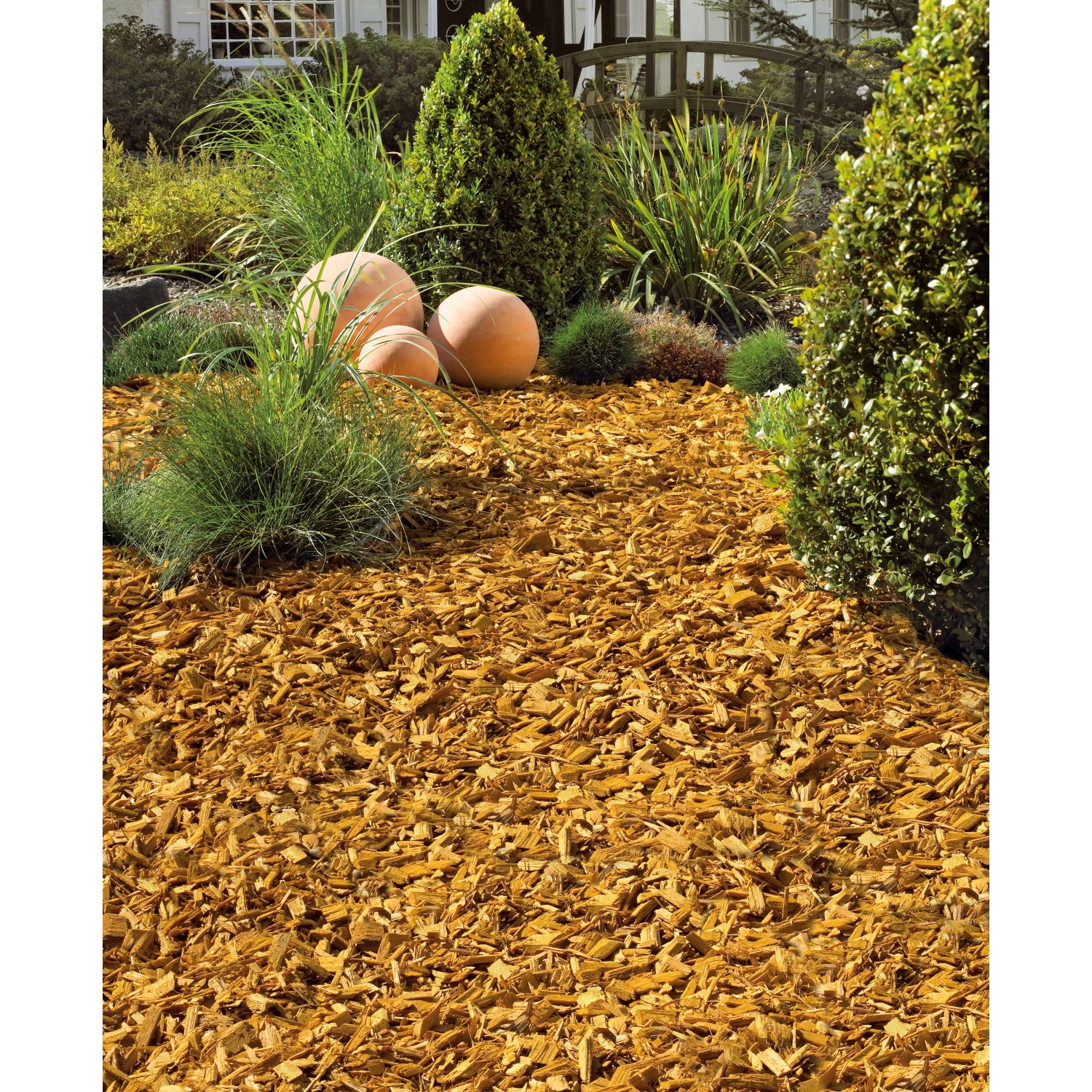 OBI Gartendekor Ahorn: Gelber Dekormulch auf Beet mit Pflanzen und Deko-Kugeln.