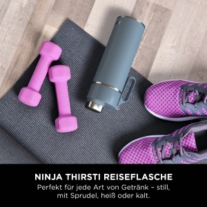 Blaue Ninja Thirsti Trinkflasche 530ml mit Hanteln und Sportschuhen auf einer Yogamatte.